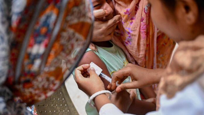 Health workers administering measles vaccination to children during district immunisation drive in Unakoti border villages