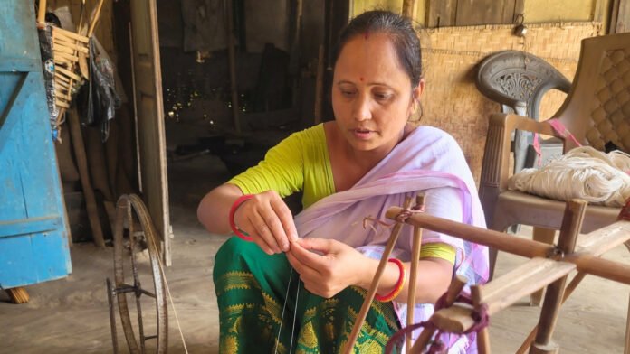 Assam handloom artisan Kamini Nath works on a traditional loom after receiving a grant to expand her weaving enterprise