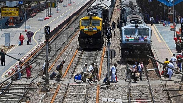 AA2bCgUT Vande Bharat Express train's passengers cross railway tracks upon their arrival at the Delhi Cantt station in New Delhi